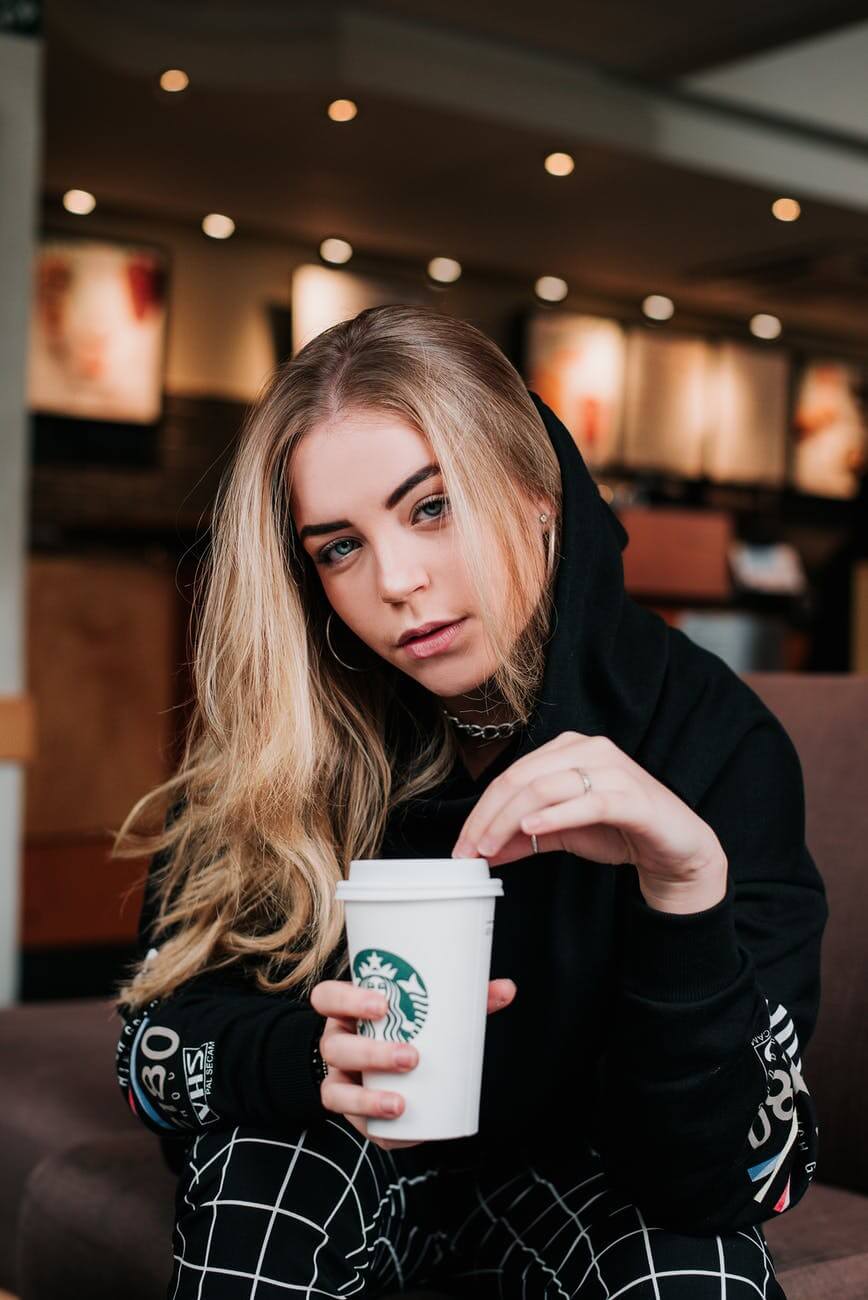 photo of sitting woman holding a starbucks to go cup